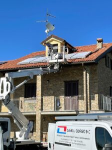 installazione di impianto solare termico su una casa in pietra, con operai al lavoro su una piattaforma elevatrice. Mezzi della ditta Cavelli Giorgio & C in primo piano.